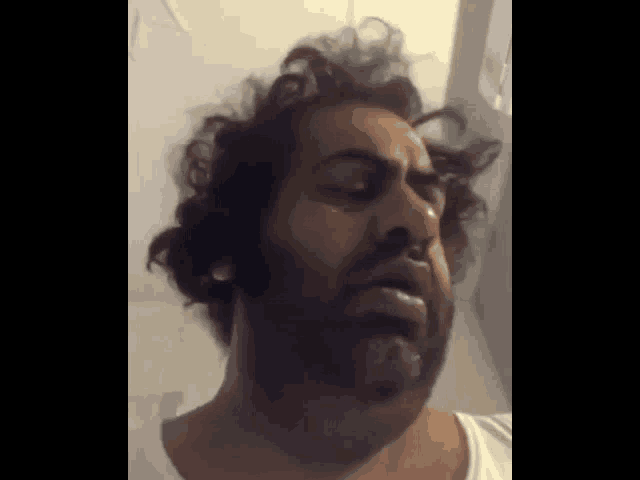 a man with a beard and a white shirt is making a funny face