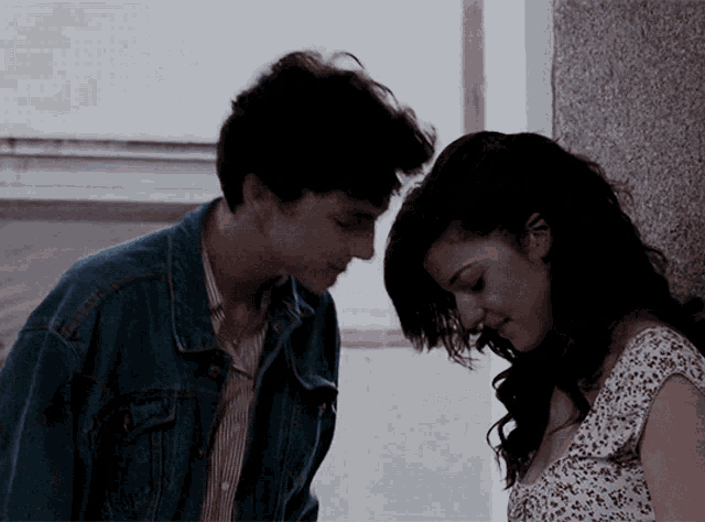 a man and a woman are leaning against a wall