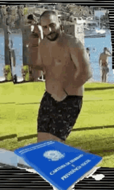 a shirtless man is standing next to a blue passport on a beach .