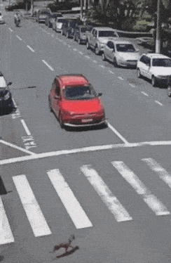 a red car is driving down a street with a sign that says ' a ' on it