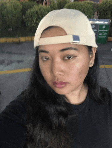 a woman wearing a white hat and a black shirt looks at the camera