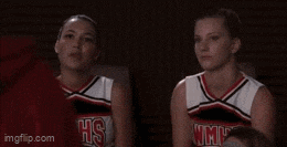 two cheerleaders are sitting next to each other wearing jhs uniforms .