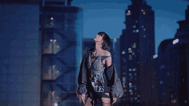 a woman stands in front of a city skyline wearing a t-shirt that says angels