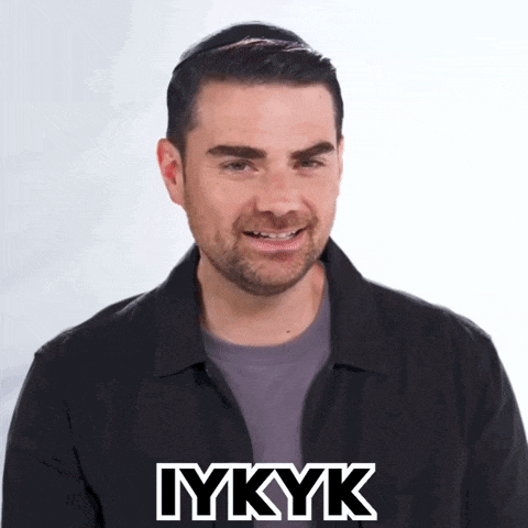 a man in a black jacket is smiling with the word iykyk above his head