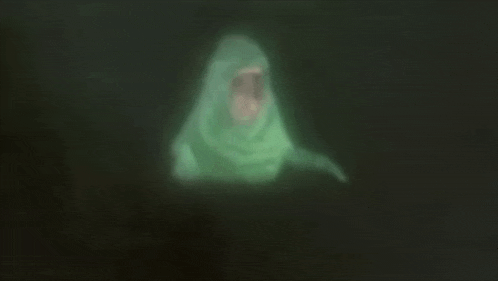 a ghost is glowing in the dark and is wrapped in a green blanket .