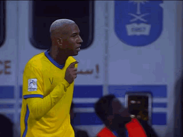 a man in a yellow shirt stands in front of an ambulance that says bxt on it