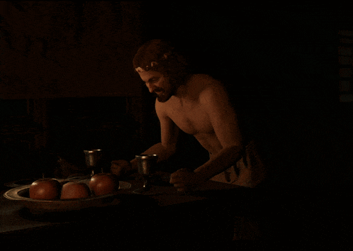 a man without a shirt is standing in front of a bowl of apples