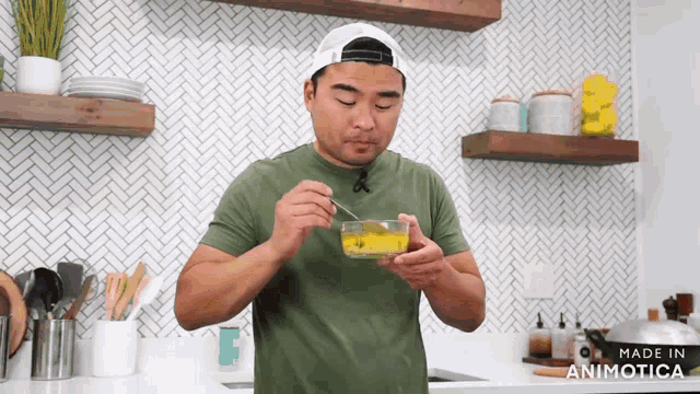 a man in a green shirt is holding a bowl with a spoon in it and the words made in animatica on the bottom right