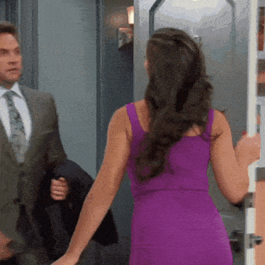 a woman in a purple dress is standing in front of a door