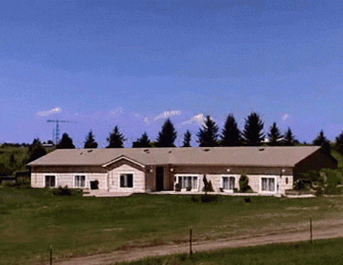 a large house sits in the middle of a grassy field with trees in the background