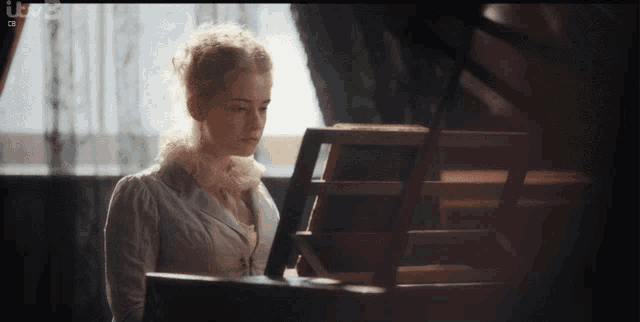 a woman in a white dress is playing a piano with a bbc logo in the corner