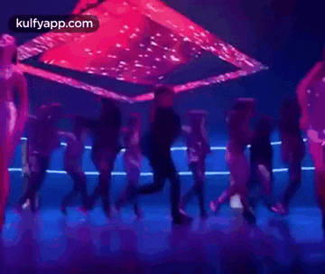 a man is dancing in front of a crowd of people in a dark room .