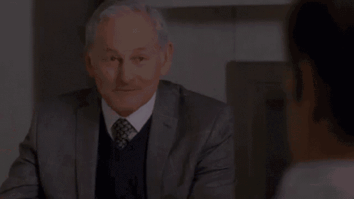 a man in a suit and tie is holding a glass of wine and says very wool