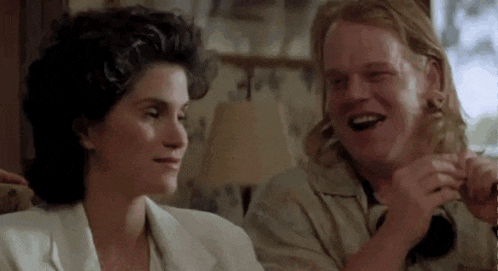 a man and a woman are sitting next to each other in a living room and laughing .