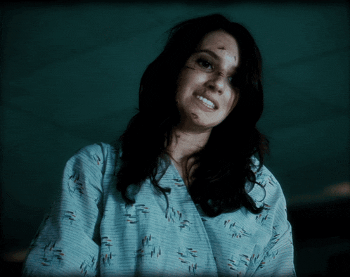 a woman in a hospital gown is smiling and has a scar on her nose