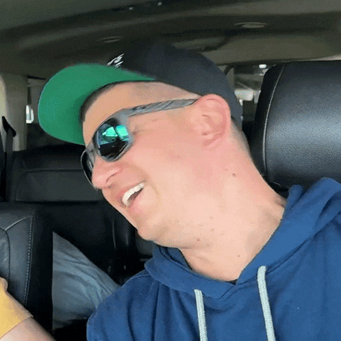 a man wearing a hat and sunglasses is laughing