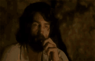 a man with a beard is holding a glass of wine in his hand .