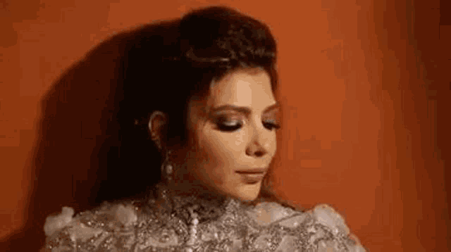 a woman in a wedding dress is standing in front of a red wall .
