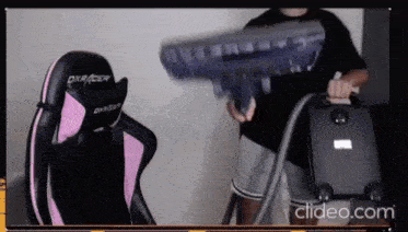 a man is holding a vacuum cleaner in front of a chair that says dxracer on it