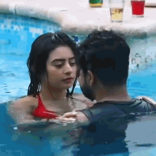 a man and woman are kissing in a pool .