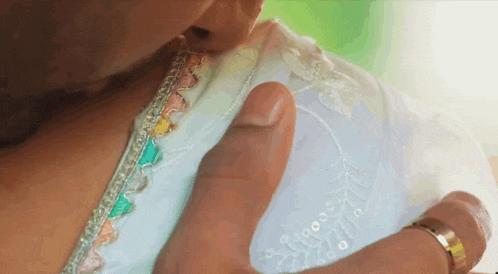 a woman is kissing a man 's hand on her shoulder .