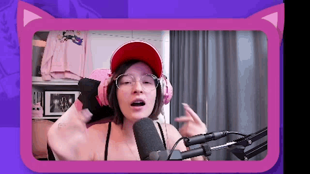 a woman wearing headphones and a red hat is talking into a microphone ..