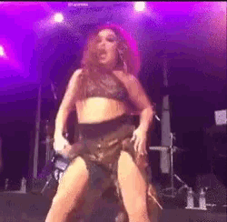 a woman is dancing on a stage with purple lights behind her