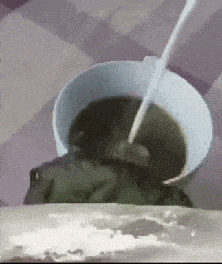 a frog is sitting in a bowl of soup with a spoon