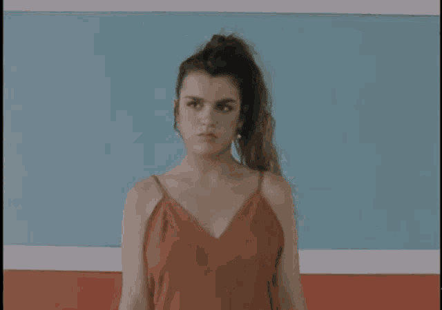 a woman in a red dress is making a sad face in front of a blue and red wall