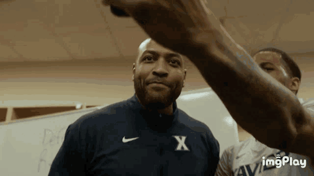 a man wearing a nike jacket with the letter x on his chest