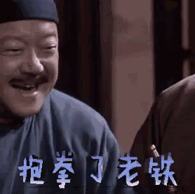 a man with a mustache and a hat is smiling with chinese characters behind him .