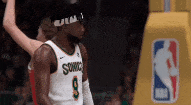 a basketball player wearing a headband and a sonics jersey is standing on the court .