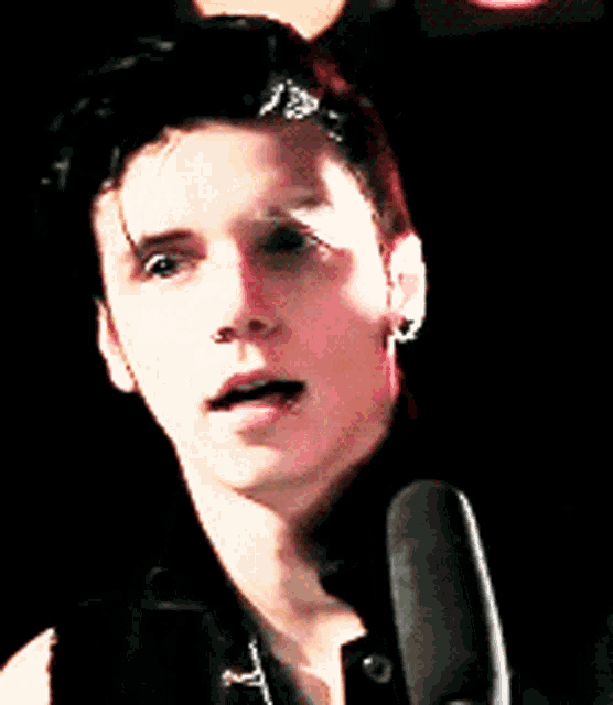 a close up of a man 's face with a microphone behind him