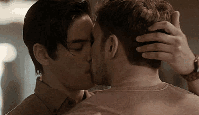 a man kissing another man on the forehead in a close up