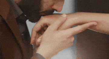 a man kisses a woman 's hand with a red spot on it