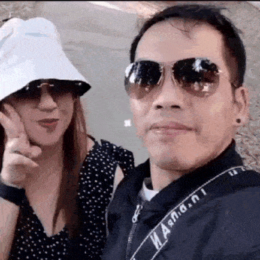 a man and a woman wearing sunglasses are posing for a picture together .