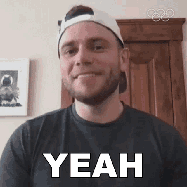 a man with a beard wearing a baseball cap and a black shirt says yeah
