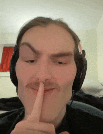 a man wearing headphones and a nose ring holds his finger to his mouth
