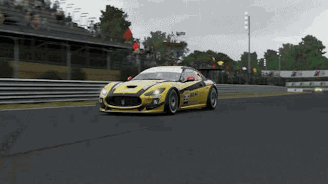 a yellow race car with the number 23 on the side is driving down a track