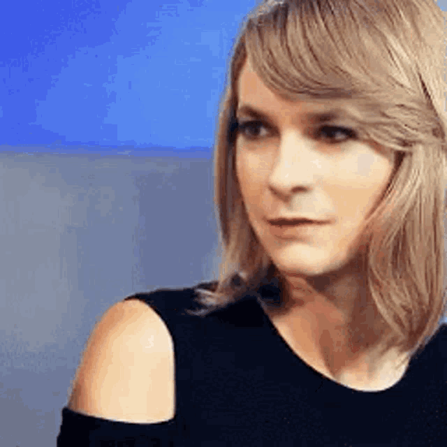 a woman with blonde hair is wearing a black tank top and looking at the camera .