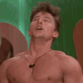a shirtless man with his mouth open and ear buds on his neck