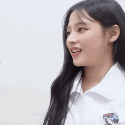 a close up of a young girl wearing a white shirt and smiling .