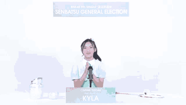 a girl stands in front of a microphone and a sign that says senbatsu general election