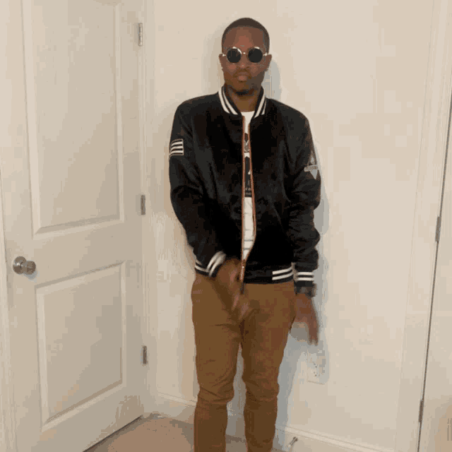 a man wearing sunglasses and a black jacket stands in a room