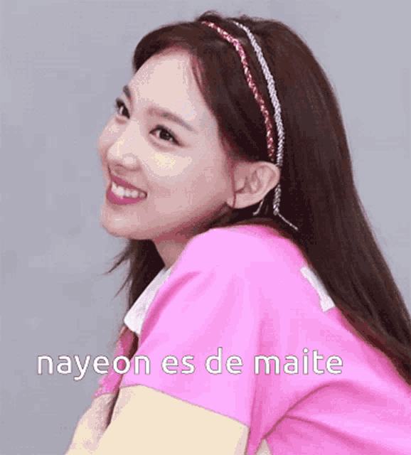 a woman wearing a pink shirt and a headband with the words nayeon es de maite written on it