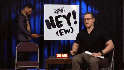 a man sitting in front of a sign that says hey ew