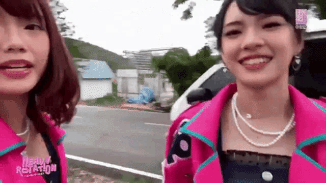 two women are standing next to each other on the side of a road .