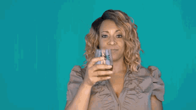 a woman is holding a glass of orange juice in front of her face