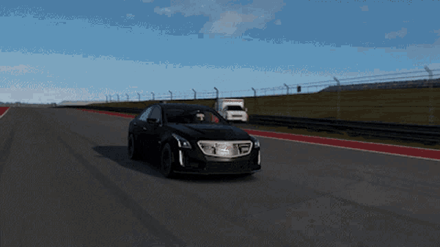 a black car is driving down a race track with a white truck in the background