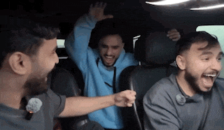 a group of men are sitting in the back seat of a car laughing .